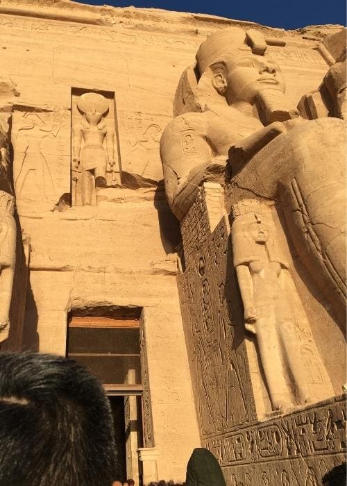 アブシンベル神殿の入り口にそびえるラムセス2世の巨大な石像の横を見上げながら通り過ぎる